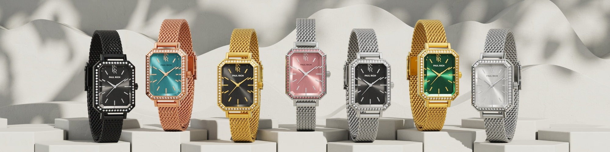Paul Rich rectangular mesh watches in black, rose gold, gold, and silver with various dial colors, displayed on white pedestals. Paul Rich rectangular mesh watches in black, rose gold, gold, and silver with various dial colors, displayed on white pedestals.