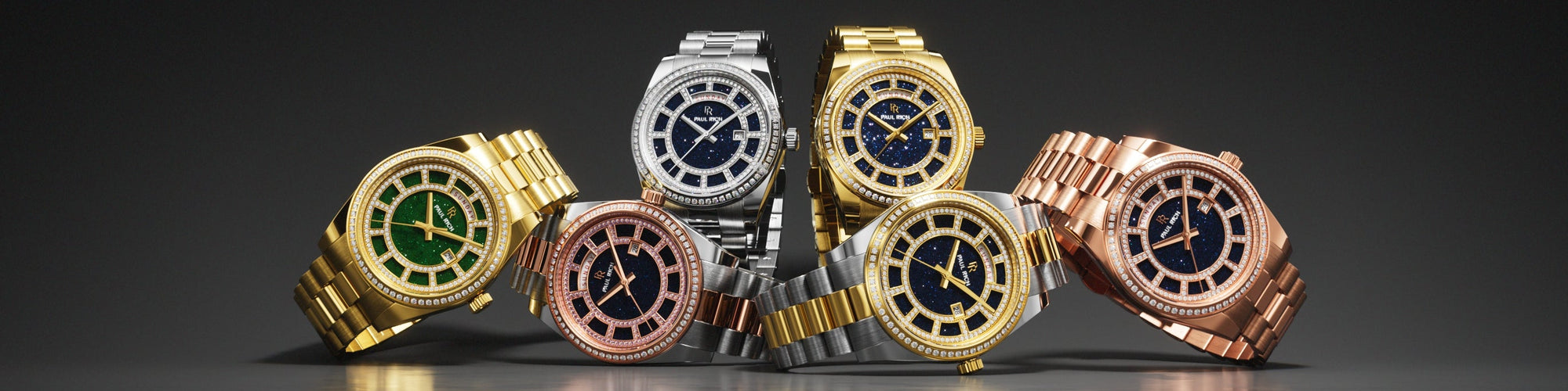 Four Paul Rich rainbow bezel watches in silver, rose gold, gold, and black, displayed on crystal surface with gray background. Four Paul Rich rainbow bezel watches in silver, rose gold, gold, and black, displayed on crystal surface with gray background.