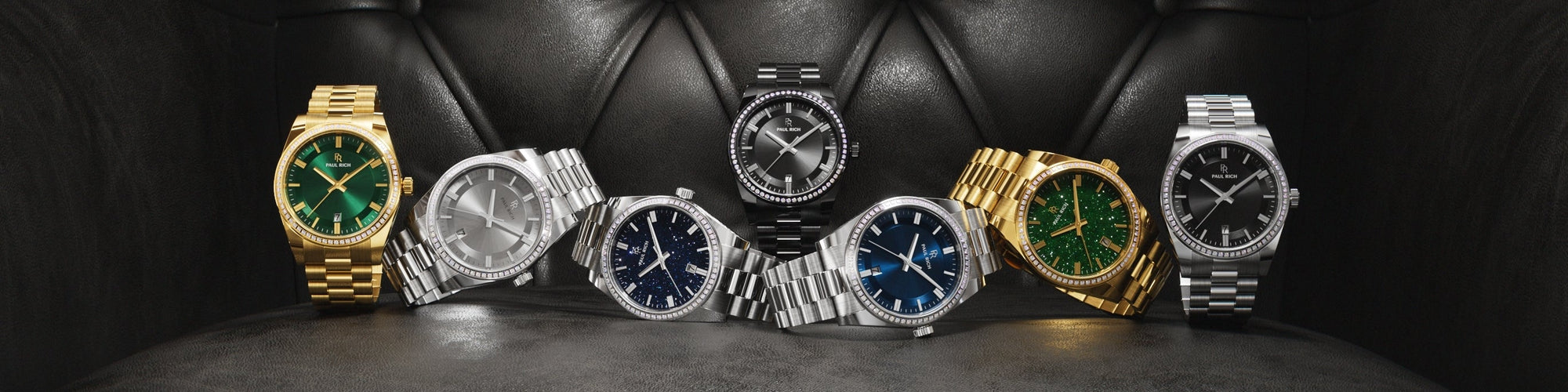 Paul Rich rainbow bezel watches in silver, rose gold, yellow gold, and black, displayed on crystal surface with gray gradient background. Paul Rich rainbow bezel watches in silver, rose gold, yellow gold, and black, displayed on crystal surface with gray gradient background.
