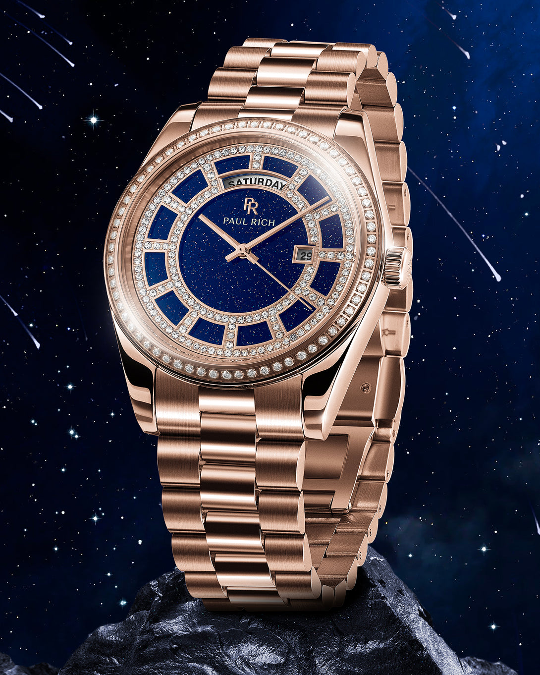 Rose-gold watch with a blue aventurine dial, pavé diamond bezel, and day–date display, shown on a matching rose-gold bracelet against a starry background. Rose-gold watch with a blue aventurine dial, pavé diamond bezel, and day–date display, shown on a matching rose-gold bracelet against a starry background.