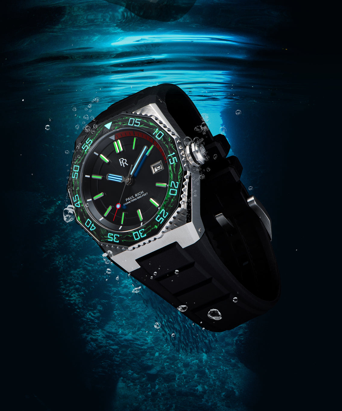 Paul Rich dive watch underwater with glowing green lume on bezel and markers, red dive timer, and black strap surrounded by bubbles. Paul Rich dive watch underwater with glowing green lume on bezel and markers, red dive timer, and black strap surrounded by bubbles.
