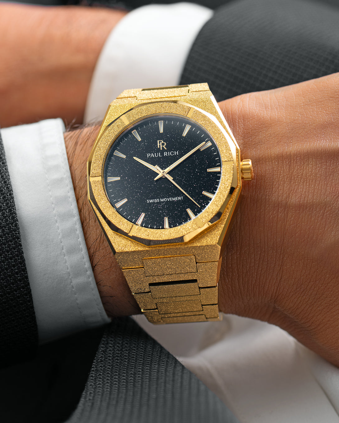 Gold Paul Rich watch with black aventurine dial and frosted finish, worn on wrist with a suit jacket and white cuff. Gold Paul Rich watch with black aventurine dial and frosted finish, worn on wrist with a suit jacket and white cuff.