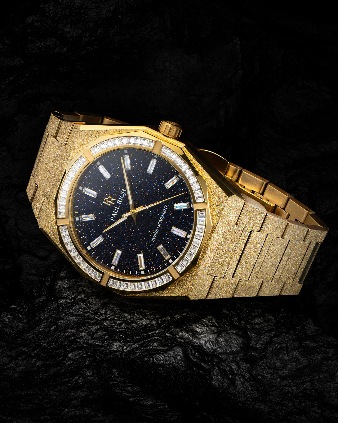 Gold frosted watch with aventurine dial and baguette-cut moissanite bezel, displayed on a dark textured surface. Gold frosted watch with aventurine dial and baguette-cut moissanite bezel, displayed on a dark textured surface.