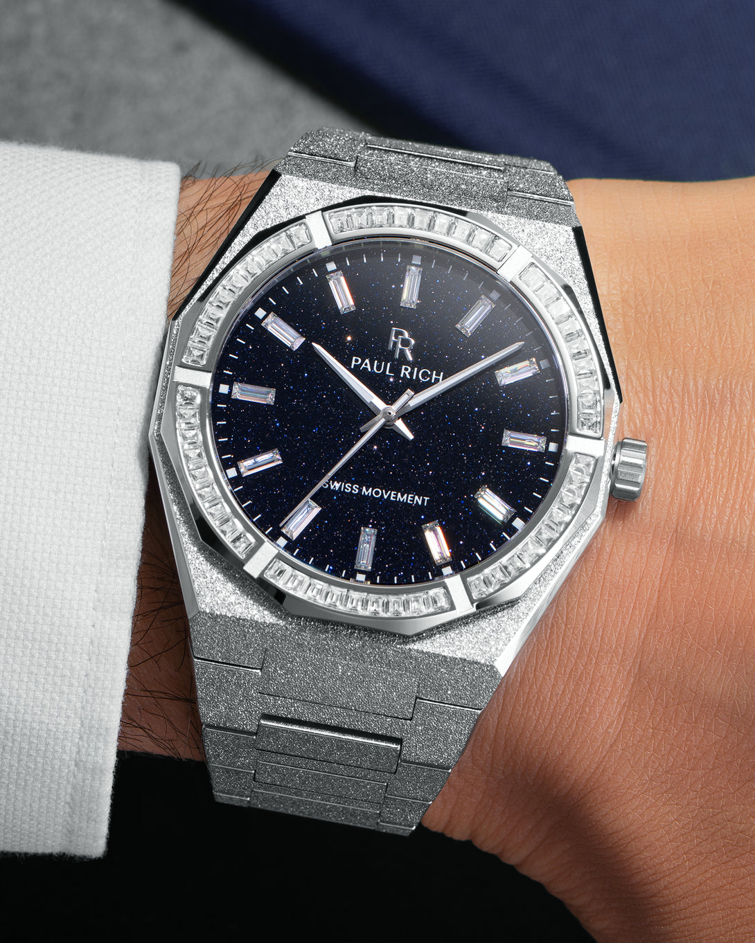 Silver frosted watch with aventurine dial and baguette-cut moissanite bezel, worn on wrist with white cuff. Silver frosted watch with aventurine dial and baguette-cut moissanite bezel, worn on wrist with white cuff.