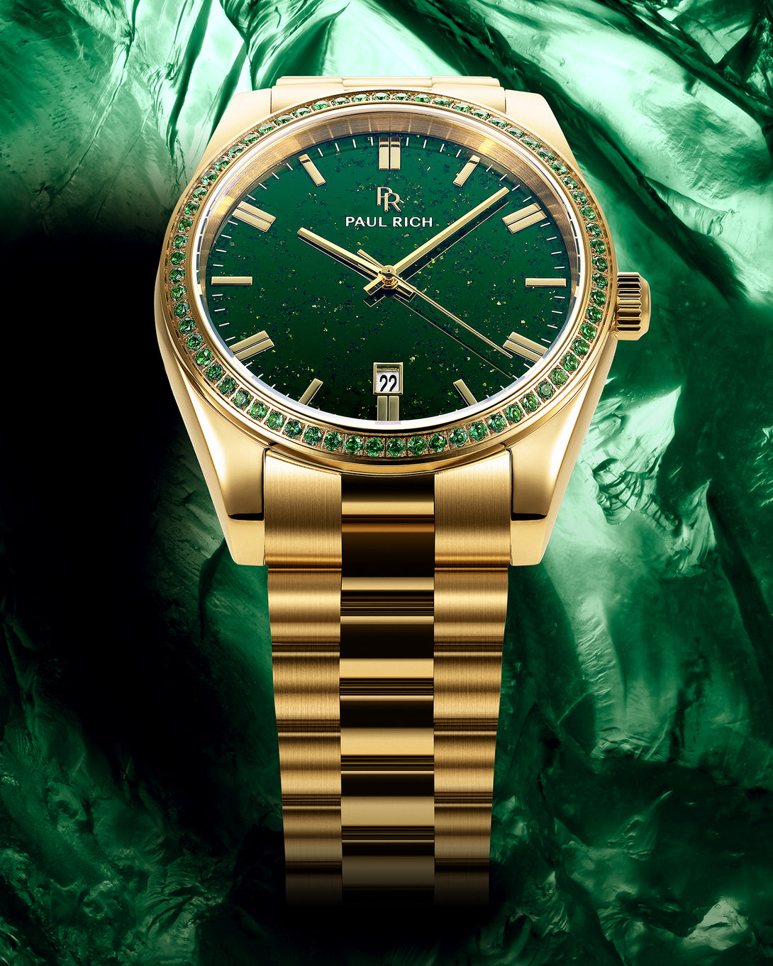 Gold watch with green aventurine dial and green gemstone-set bezel on a gold bracelet, displayed against a textured green background. Gold watch with green aventurine dial and green gemstone-set bezel on a gold bracelet, displayed against a textured green background.