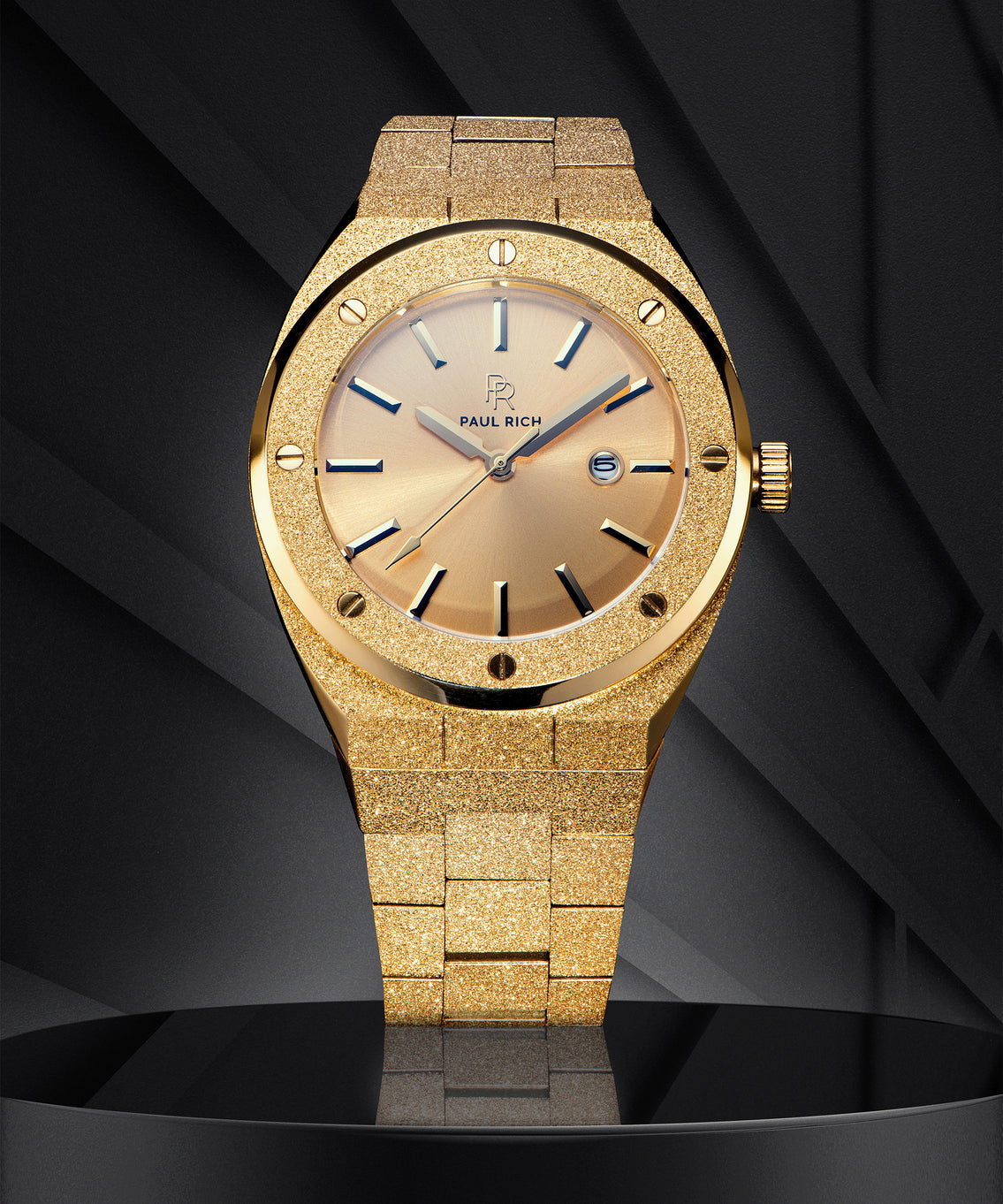 Paul Rich watch with frosted gold case and bracelet, metallic champagne gold sunray dial, and date window, displayed on a black geometric background. Paul Rich watch with frosted gold case and bracelet, metallic champagne gold sunray dial, and date window, displayed on a black geometric background.
