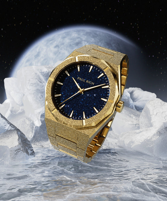 Gold Paul Rich watch with blue aventurine dial displayed on icy surface with a glowing planet and starry sky in the background. Gold Paul Rich watch with blue aventurine dial displayed on icy surface with a glowing planet and starry sky in the background.
