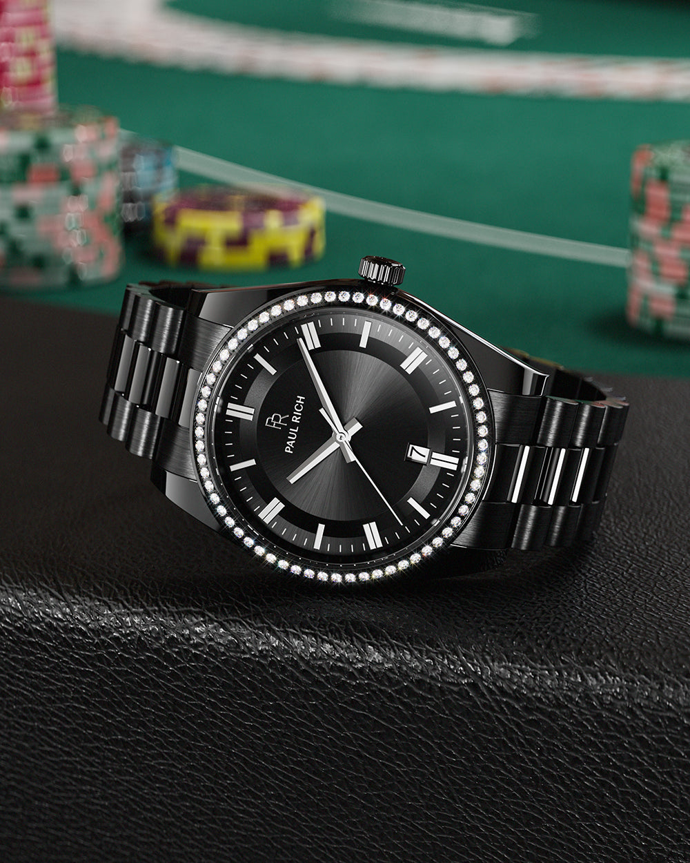 Black Paul Rich watch with black sunray dial, diamond-set bezel, and black link bracelet, displayed on a black leather surface with poker chips and a green casino table in the background. Black Paul Rich watch with black sunray dial, diamond-set bezel, and black link bracelet, displayed on a black leather surface with poker chips and a green casino table in the background.