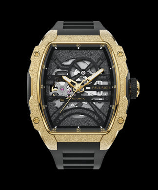 Astro Esqueleto Mason Oro Paul Rich watch with frosted gold tonneau case, skeleton dial, gold hands, and black rubber strap, shown on transparent background.