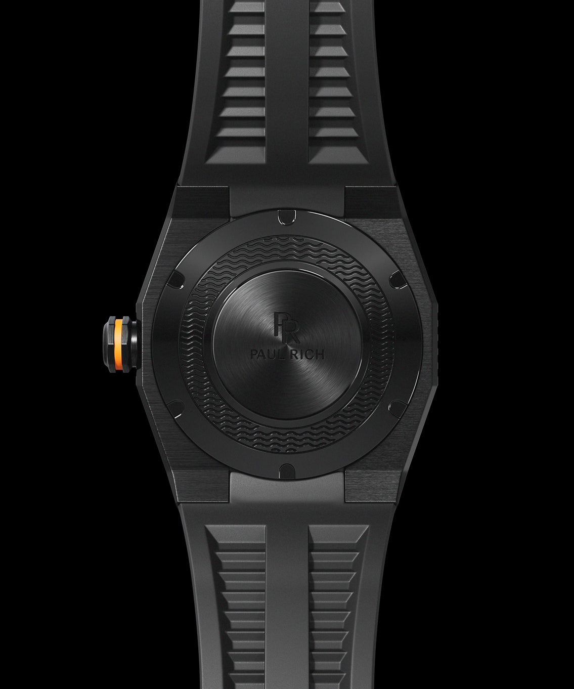 Back view of a Paul Rich dive watch with black brushed steel caseback, engraved wave pattern, and orange-accented crown. Back view of a Paul Rich dive watch with black brushed steel caseback, engraved wave pattern, and orange-accented crown.