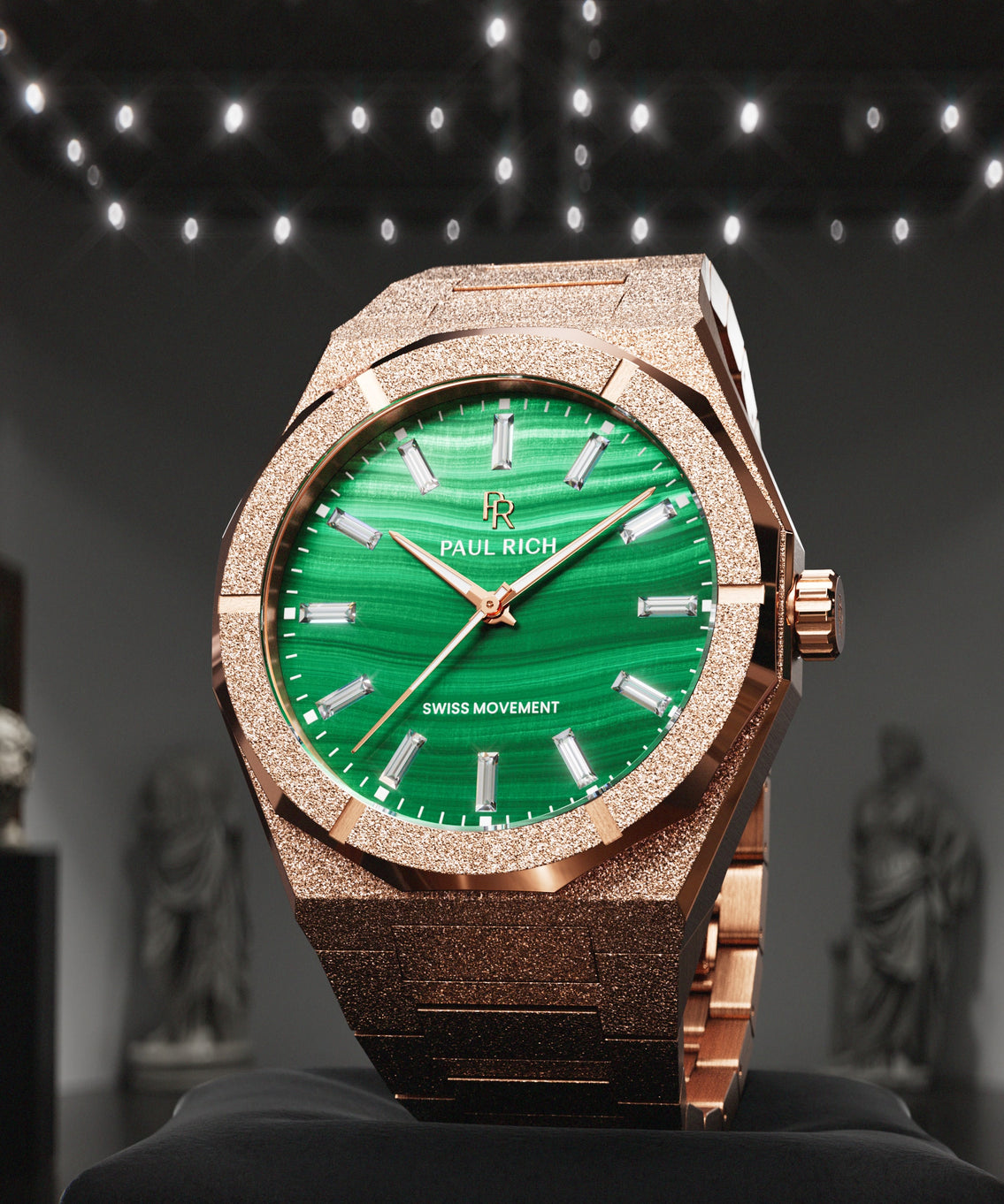Rose-gold-tone Malachite Aurora watch on a black cushion in a gallery with statues Rose-gold-tone Malachite Aurora watch on a black cushion in a gallery with statues
