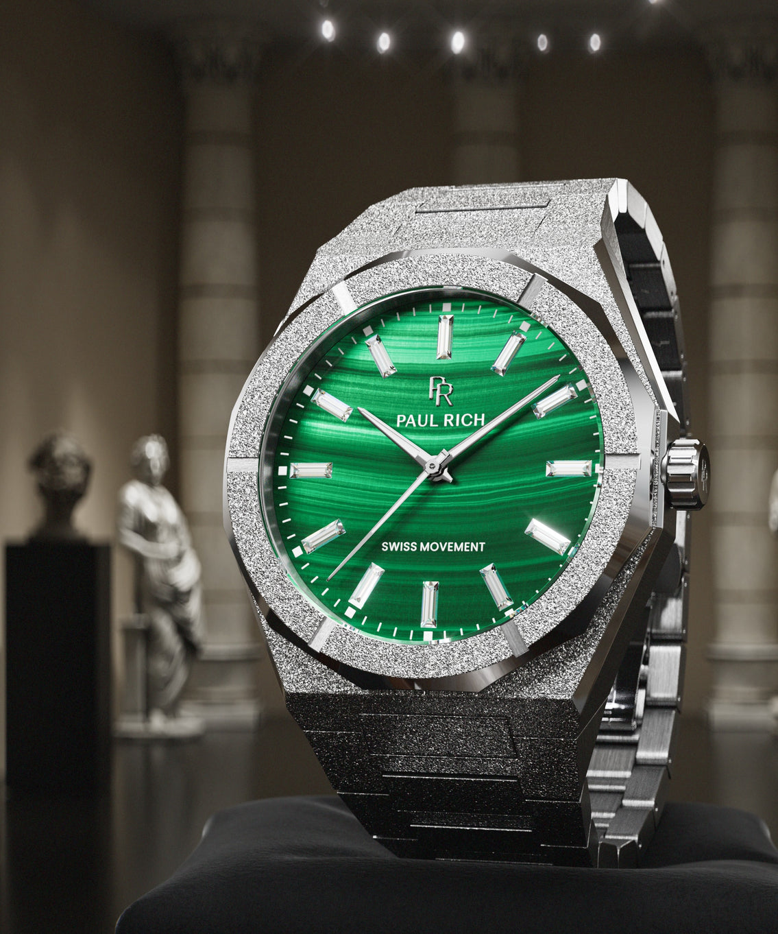 Silver Malachite Aurora watch on a black cushion in a gallery with statues Silver Malachite Aurora watch on a black cushion in a gallery with statues
