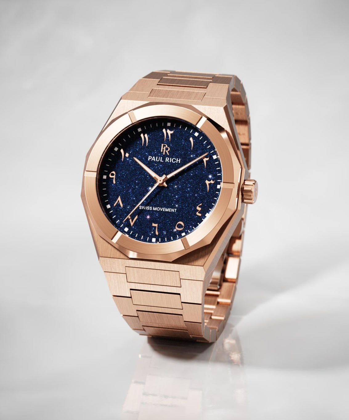 Paul Rich watch with brushed rose gold case and bracelet, featuring a blue aventurine dial with Arabic numerals, displayed on a white surface. Paul Rich watch with brushed rose gold case and bracelet, featuring a blue aventurine dial with Arabic numerals, displayed on a white surface.