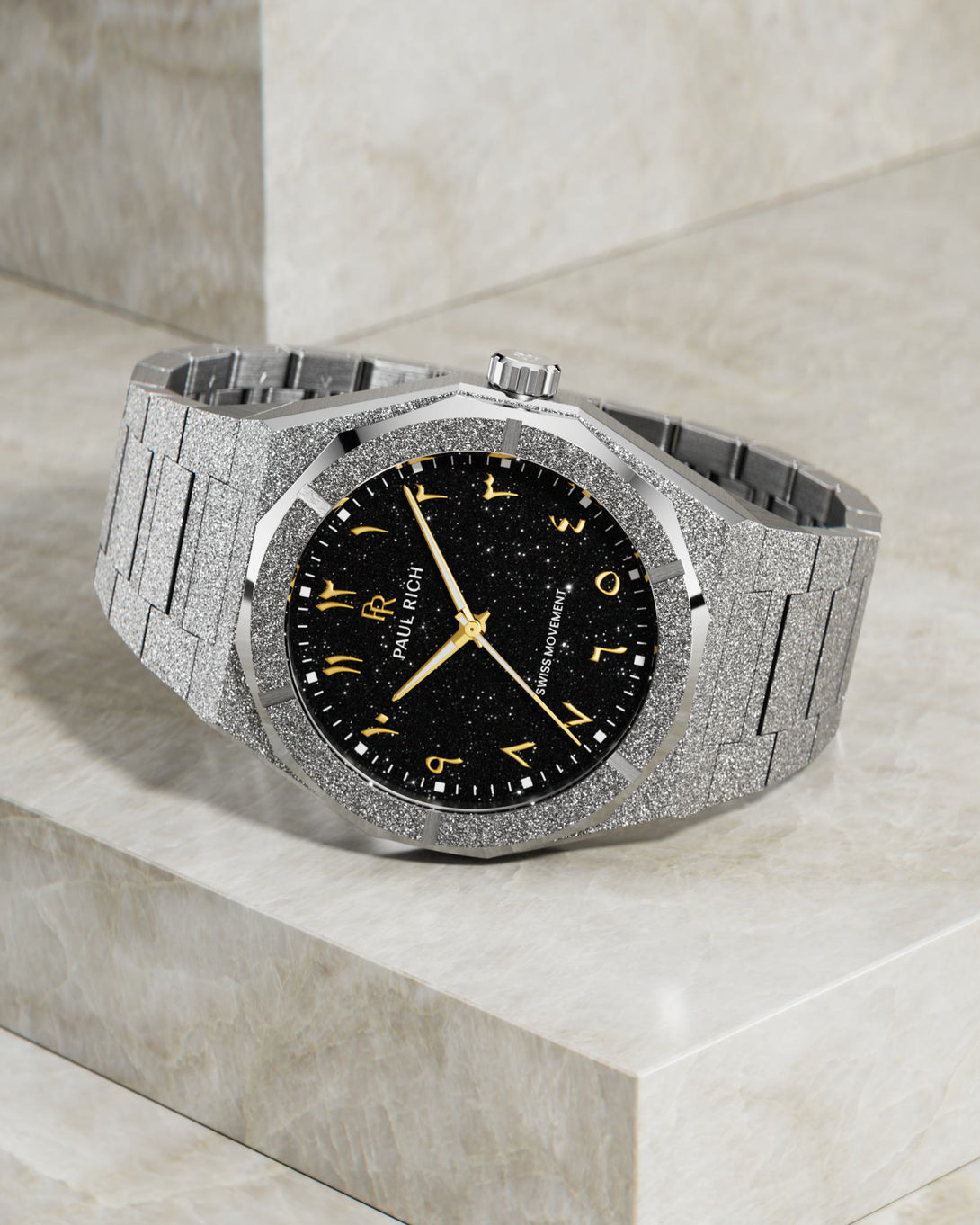 Paul Rich frosted silver watch with gold Arabic numerals and black aventurine dial, displayed on marble-textured stone surface. Paul Rich frosted silver watch with gold Arabic numerals and black aventurine dial, displayed on marble-textured stone surface.