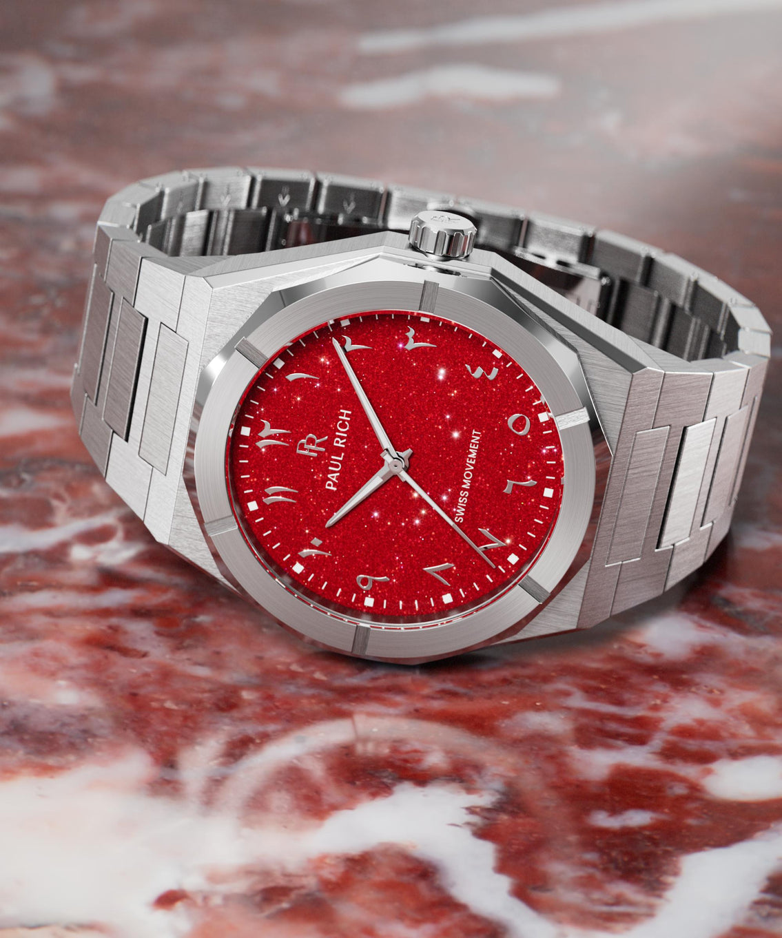 Paul Rich watch with brushed silver case and sparkling red dial featuring Arabic numerals, displayed on a polished red marble surface. Paul Rich watch with brushed silver case and sparkling red dial featuring Arabic numerals, displayed on a polished red marble surface.