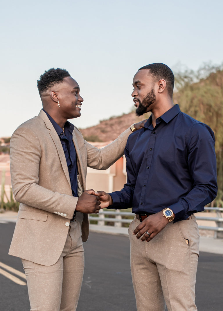 Two stylish men greeting each other on a suburban street; one wears a navy shirt and gold Paul Rich watch with blue dial. Two stylish men greeting each other on a suburban street; one wears a navy shirt and gold Paul Rich watch with blue dial.