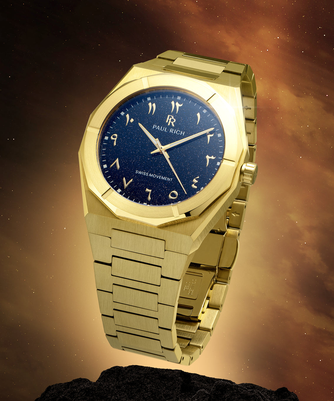 Gold Paul Rich watch with blue aventurine dial and Arabic numerals, shown on a rock with glowing space-themed background. Gold Paul Rich watch with blue aventurine dial and Arabic numerals, shown on a rock with glowing space-themed background.