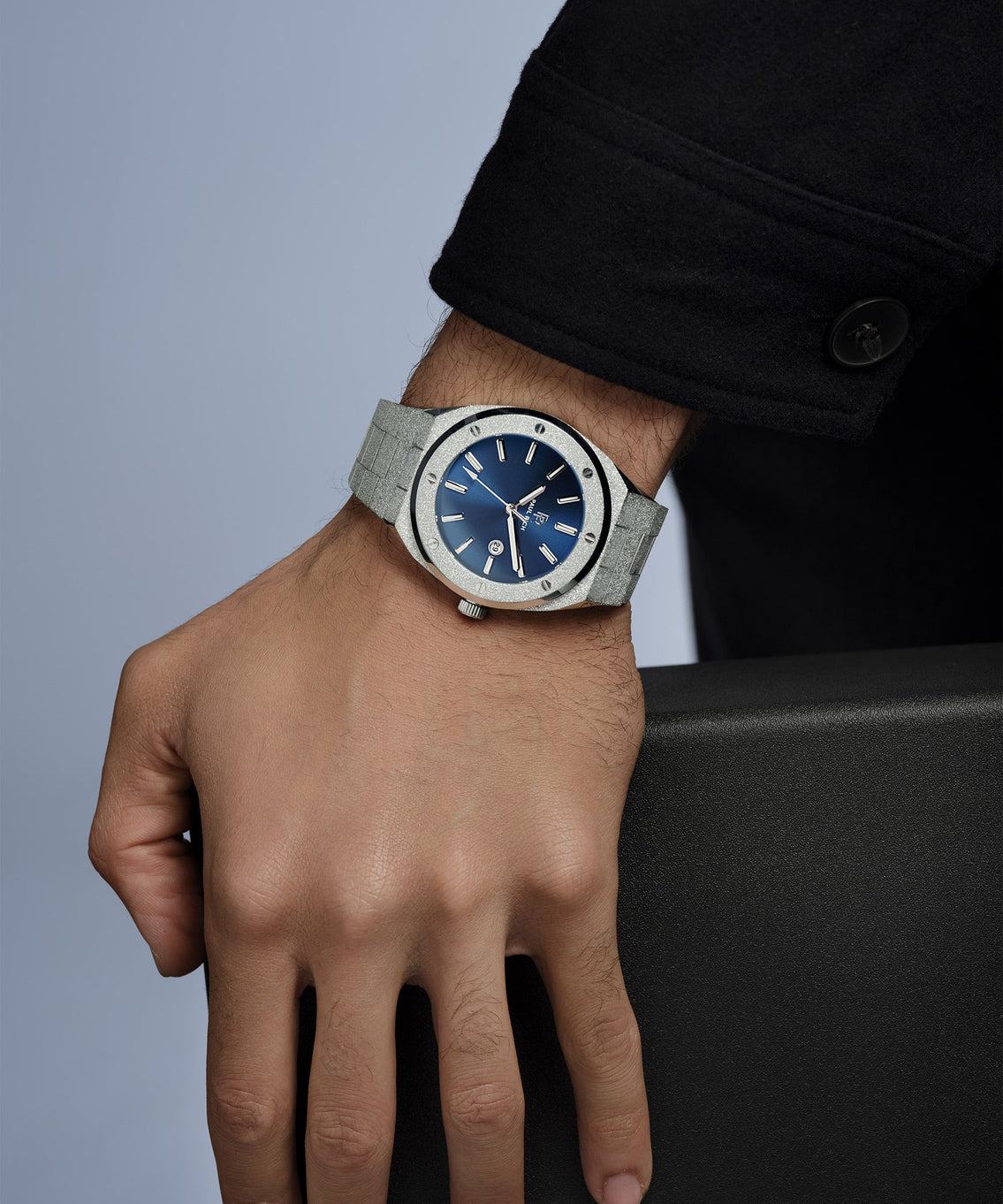 Hand wearing a watch with a blue face and gray strap on a neutral background Hand wearing a watch with a blue face and gray strap on a neutral background