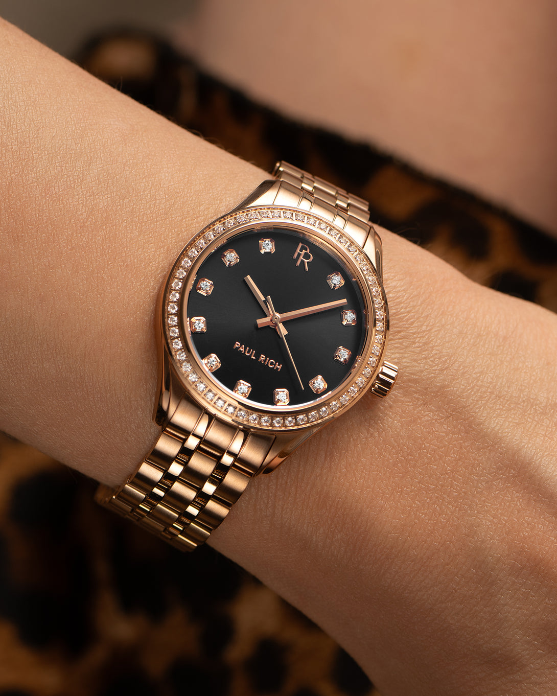 Paul Rich rose gold women’s watch with crystal hour markers and black dial, shown on wrist against leopard print background. Paul Rich rose gold women’s watch with crystal hour markers and black dial, shown on wrist against leopard print background.