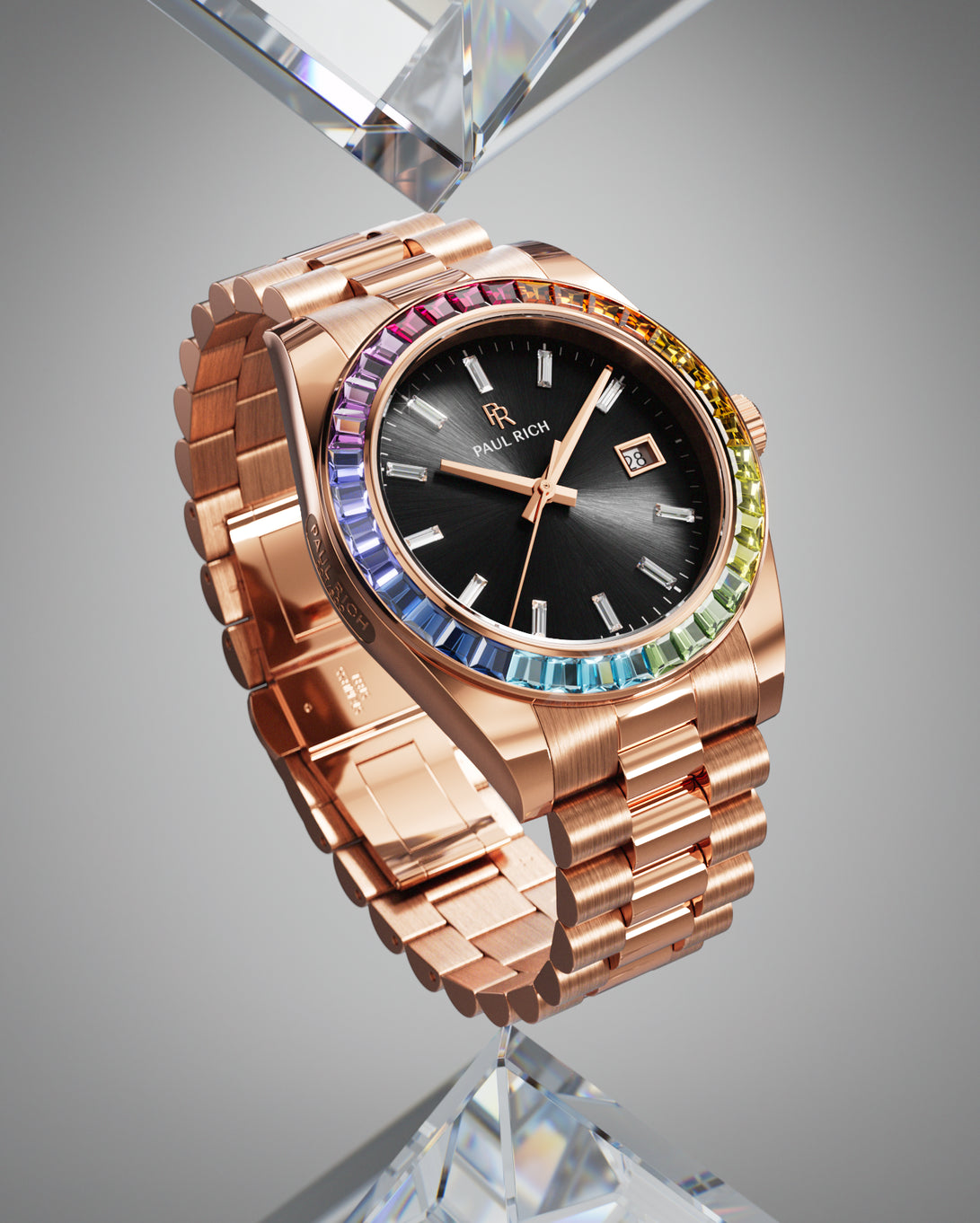 Rose gold wristwatch with a black sunburst dial, rainbow bezel, and metal bracelet displayed upright on a faceted clear crystal stand. Rose gold wristwatch with a black sunburst dial, rainbow bezel, and metal bracelet displayed upright on a faceted clear crystal stand.