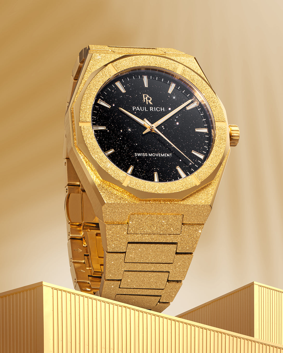 Gold Paul Rich watch with frosted case and black aventurine dial, displayed upright on a golden architectural surface with soft lighting. Gold Paul Rich watch with frosted case and black aventurine dial, displayed upright on a golden architectural surface with soft lighting.