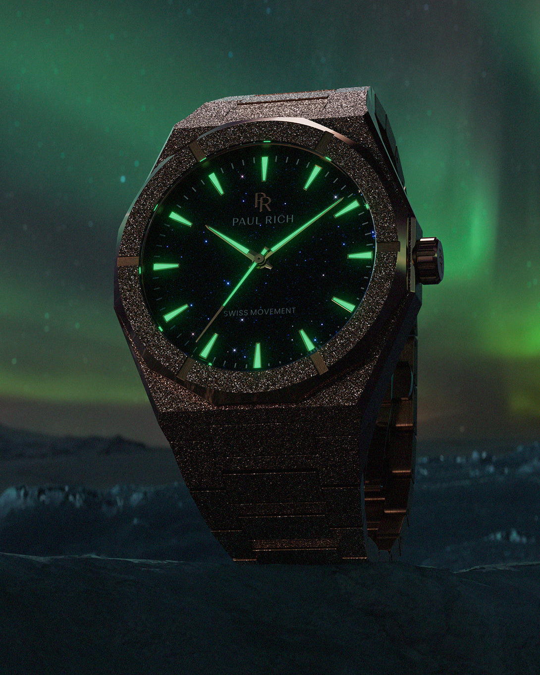 Paul Rich watch with frosted case and glowing green hands over a black aventurine dial, set against a Northern Lights backdrop. Paul Rich watch with frosted case and glowing green hands over a black aventurine dial, set against a Northern Lights backdrop.