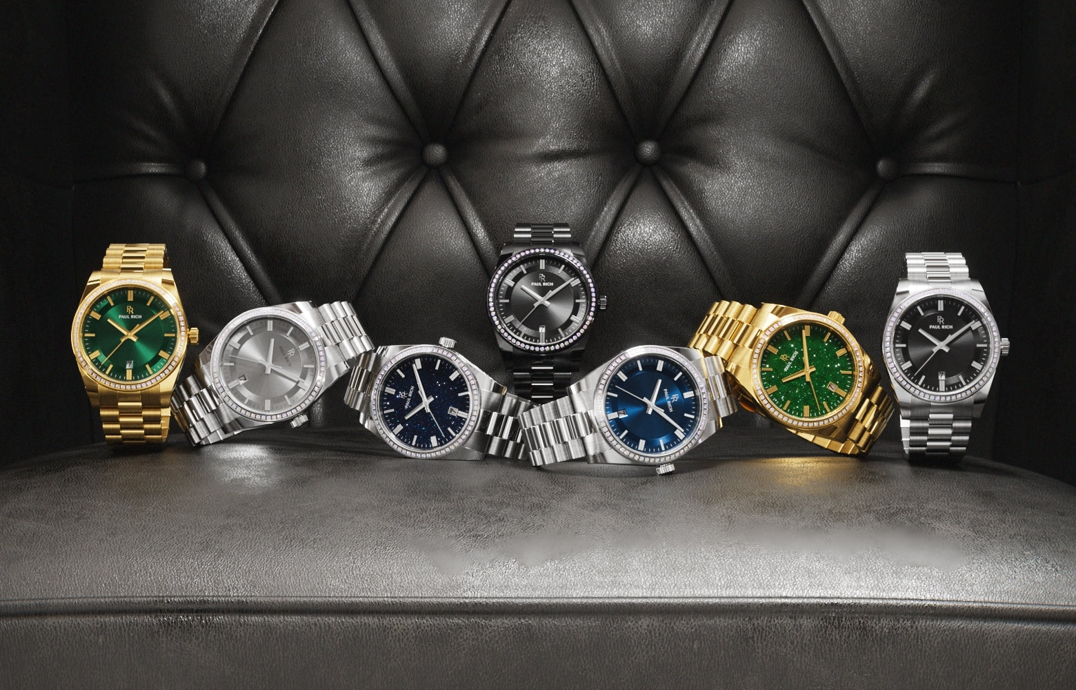 Four Paul Rich rainbow bezel watches in silver, rose gold, gold, and black with black dials, displayed on faceted crystal surface. Four Paul Rich rainbow bezel watches in silver, rose gold, gold, and black with black dials, displayed on faceted crystal surface.