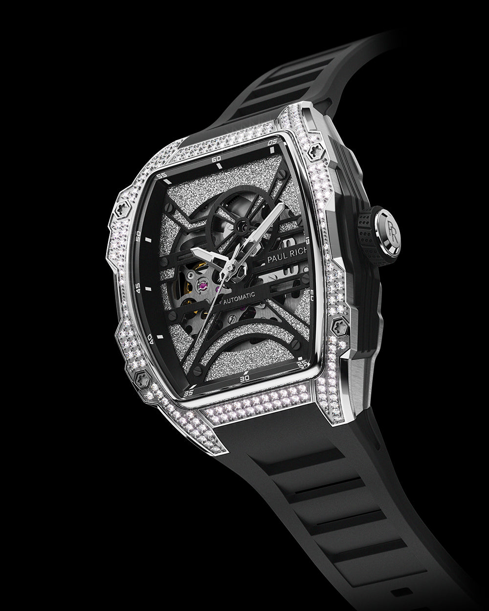 Angled view of a tonneau-shaped wristwatch with a skeleton dial, crystal-set bezel, textured metallic baseplate, and black rubber strap on a transparent background. Angled view of a tonneau-shaped wristwatch with a skeleton dial, crystal-set bezel, textured metallic baseplate, and black rubber strap on a transparent background.