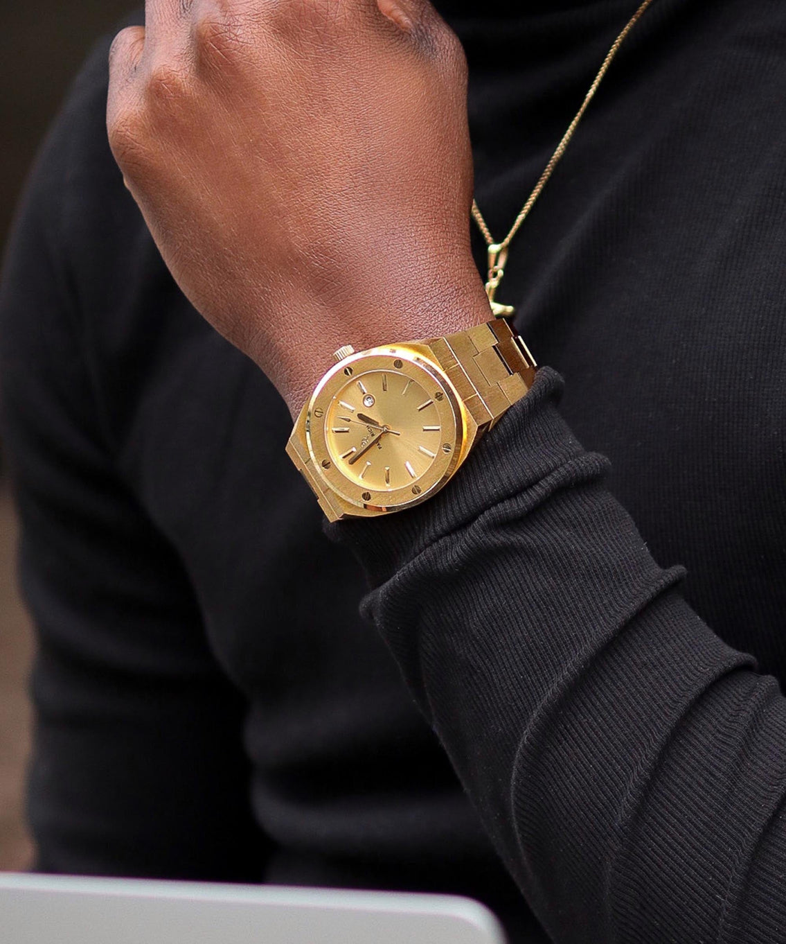 Paul Rich brushed gold watch with gold dial and date window, worn on wrist with black long sleeve shirt and gold necklace. Paul Rich brushed gold watch with gold dial and date window, worn on wrist with black long sleeve shirt and gold necklace.