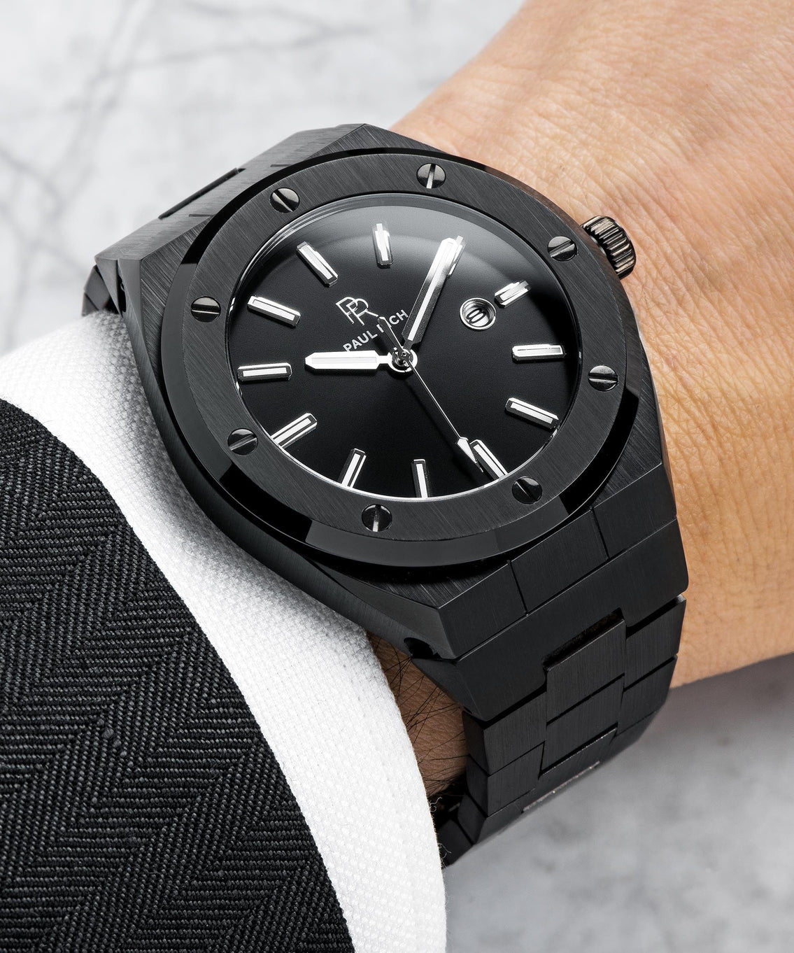 Paul Rich brushed black watch with black sunray dial and date window, worn with black suit jacket and white shirt cuff. Paul Rich brushed black watch with black sunray dial and date window, worn with black suit jacket and white shirt cuff.