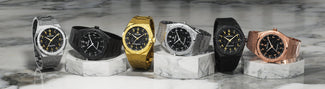 Six frosted diamond-cut watches in silver, black, gold, and rose gold colorways displayed on white marble surface.