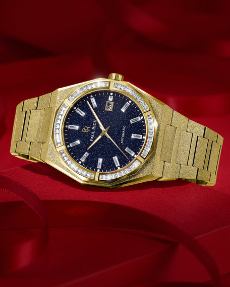 Gold frosted watch with blue aventurine dial and moissanite bezel resting on deep red fabric, highlighting its sparkle and polished finish.