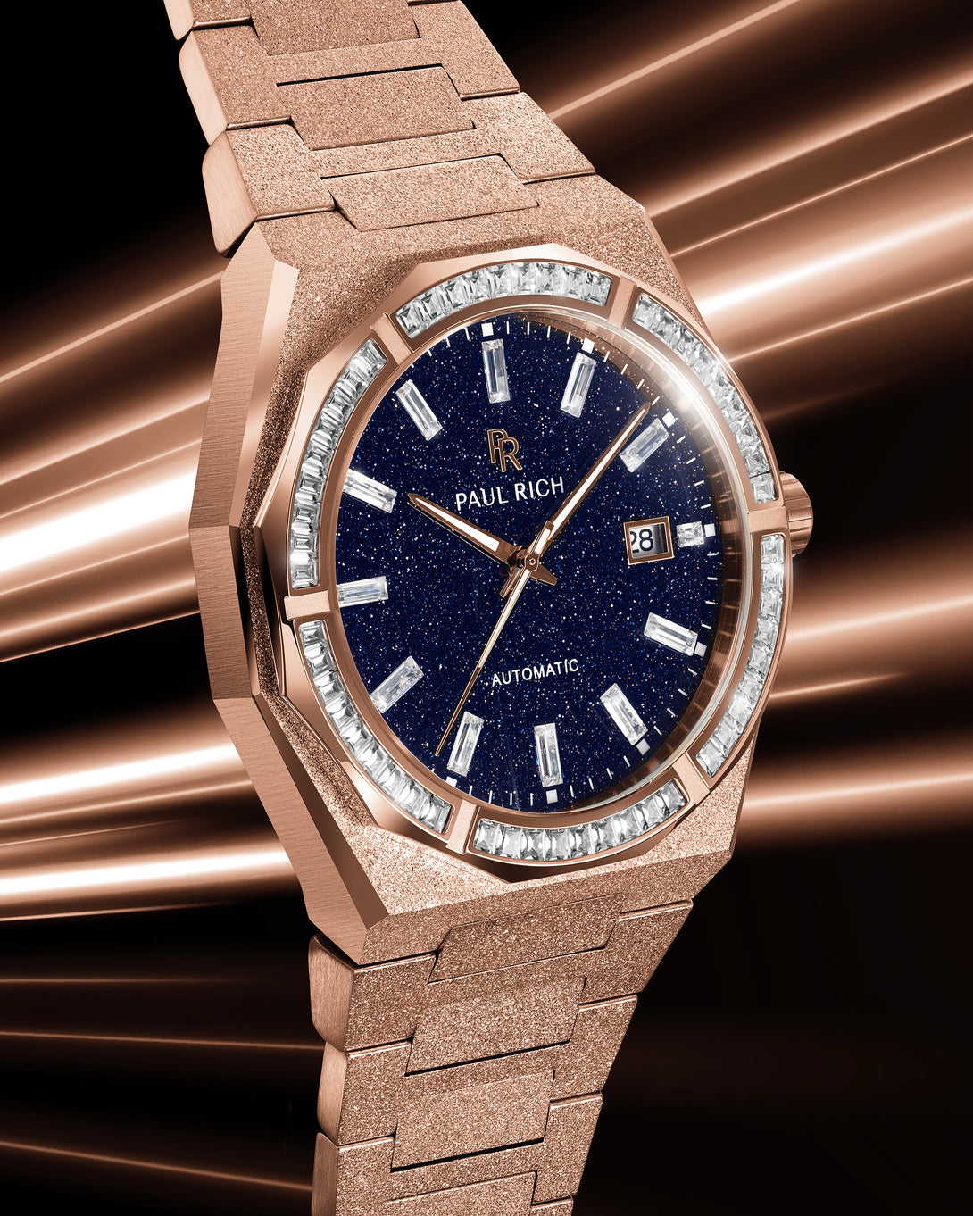 Close-up of a rose gold Paul Rich watch with a blue aventurine dial and gem-set bezel, glowing under warm streaks of light.