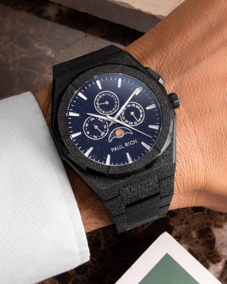 Frosted black moonphase watch on wrist with aventurine dial, calendar subdials, and diamond-dust black bracelet finish.