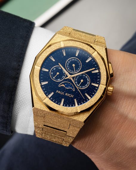 Frosted gold moonphase watch on wrist with aventurine dial, calendar subdials, and shimmering textured gold bracelet.
