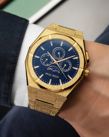 Frosted gold moonphase watch on wrist with aventurine dial, calendar subdials, and shimmering textured gold bracelet.