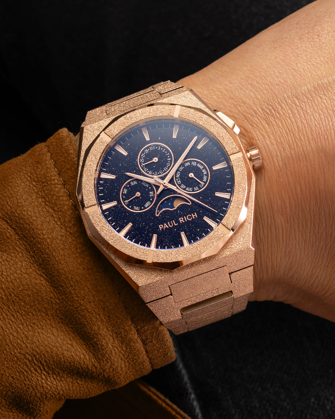 Frosted rose gold moonphase watch on wrist with aventurine dial, calendar subdials, and shimmering textured rose gold bracelet.