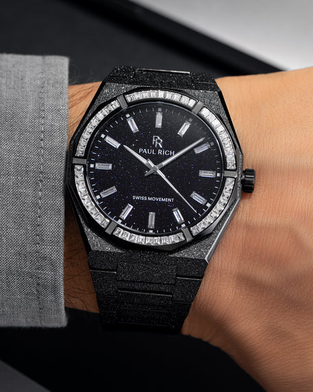 Black frosted watch with aventurine dial and moissanite bezel, worn on wrist with grey cuff.