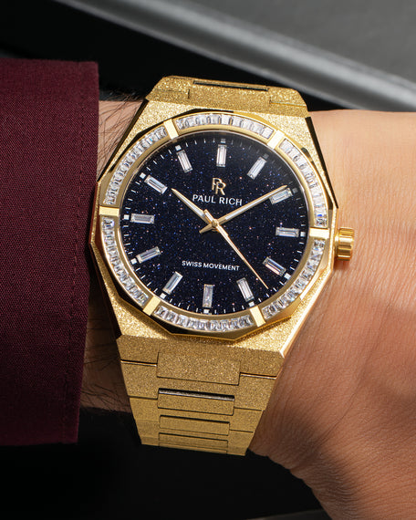 Gold frosted watch with aventurine dial and moissanite bezel, worn on wrist with burgundy cuff.