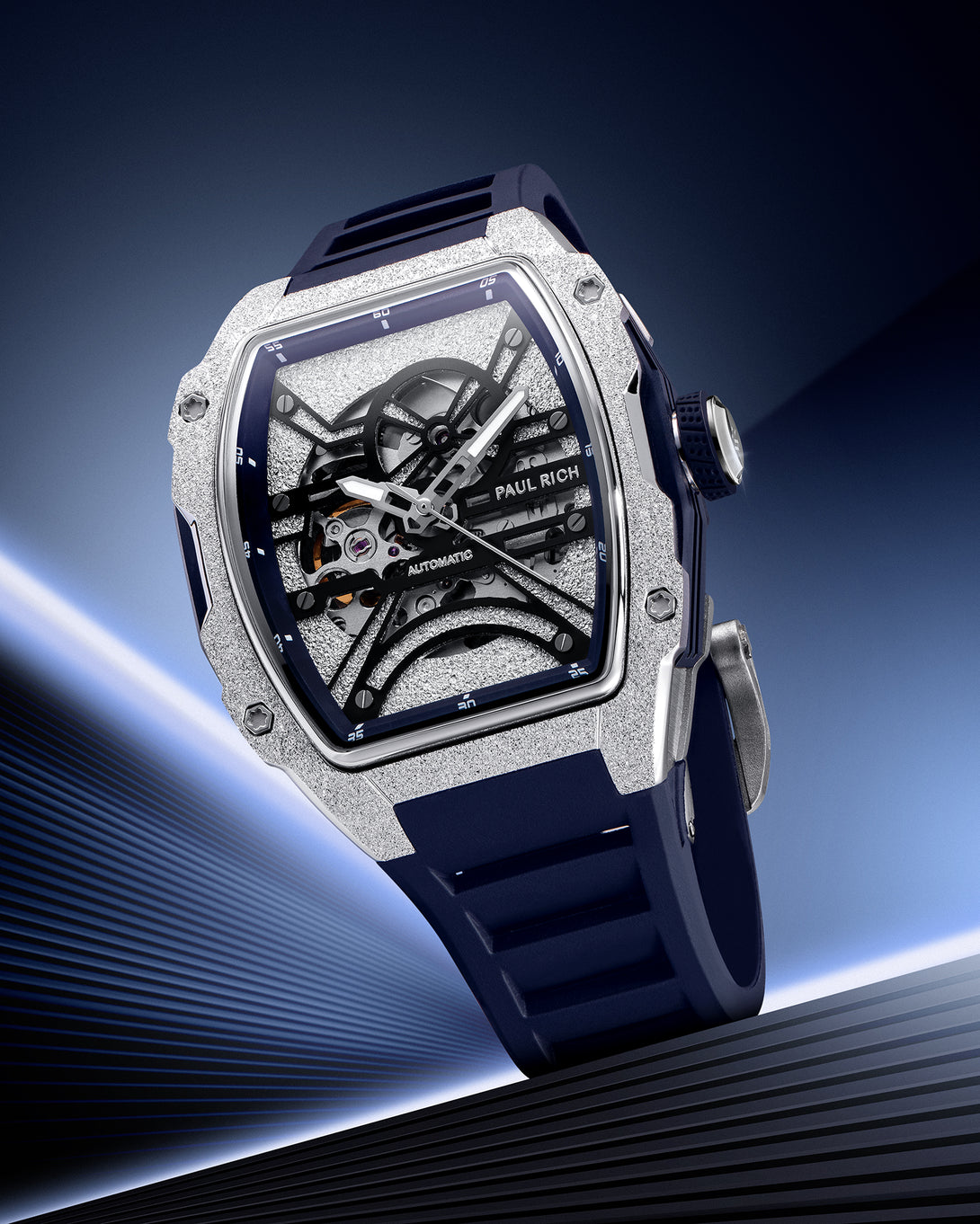 Silver frosted tonneau skeleton watch with blue strap, displayed on a gradient blue background with metallic lines.