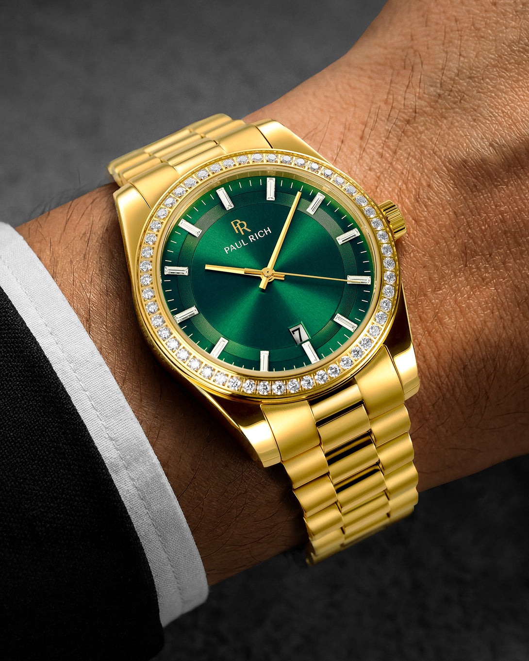 Gold watch with a green face on a wrist against a dark background