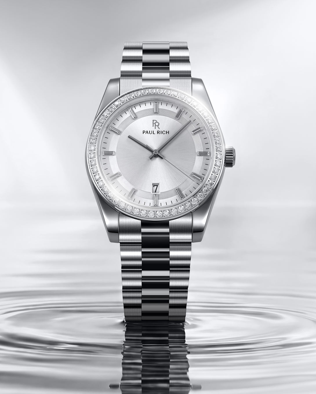 Silver watch with diamond-studded bezel on a water surface background