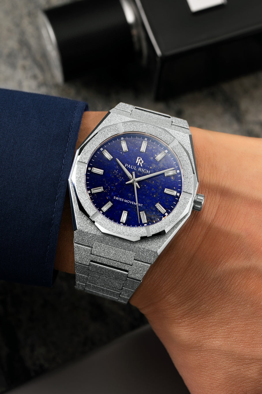 Silver Lapis Nebula watch with a blue dial worn beside a navy cuff