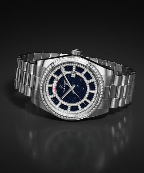 ChatGPT said: Blue aventurine dial watch with a silver metal bracelet, pavé-set bezel, day and date windows, and a polished case resting on a dark reflective surface.
