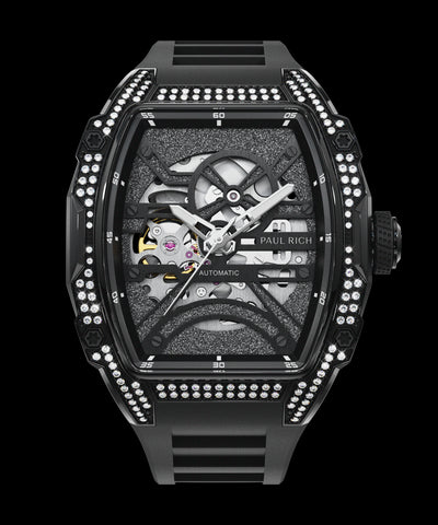 Front view of black open dial watch with silver automatic movement, black strap, and diamond-set case on white background.