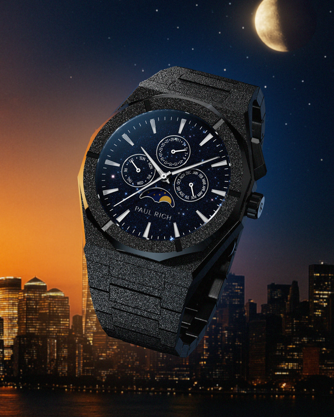 Frosted black stainless steel watch with blue aventurine dial, moonphase, and subdials, set against a city skyline at dusk with a moonlit sky.