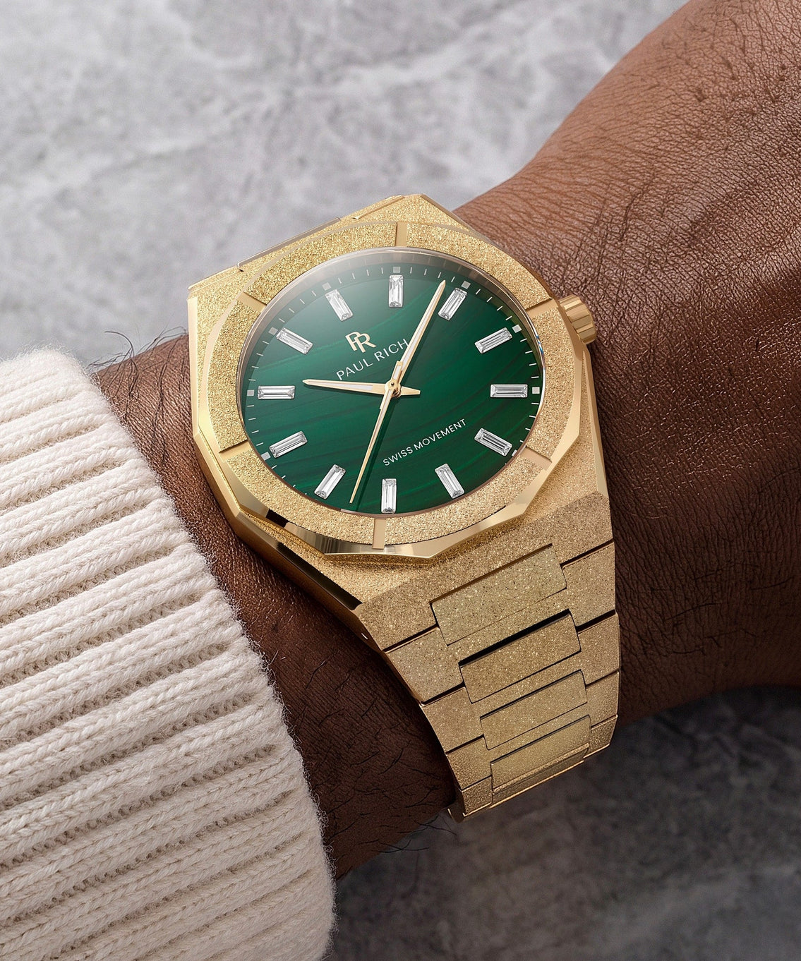 Frosted Star Dust II Malachite Aurora Gold, on the wrist against grey marble