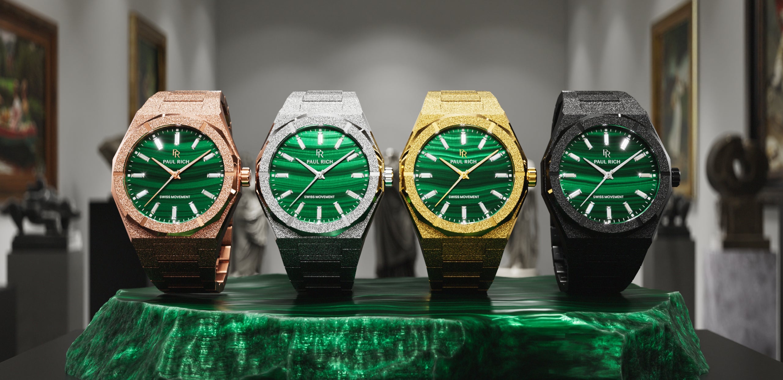 Four Malachite Aurora watches in rose gold, silver, gold and black with green malachite dials, on a malachite stone in a gallery